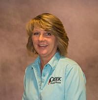 Tammy Smith, smiling woman with blonde hair and a Creek Travel Plaza polo shirt on.